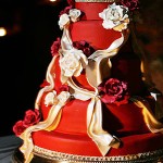 Красный свадебный торт с бежевыми лентами и розами