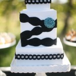 Белый свадебный торт с черной лентой и синим цветком